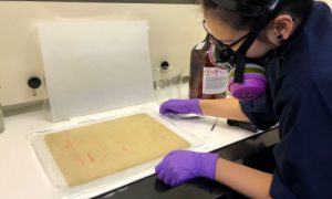 Professional Restoring an Old Document with Chemicals, While wearing a Gas Mask